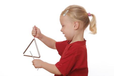 Portrait of a young girl playing a triangle on white backgroundの写真素材