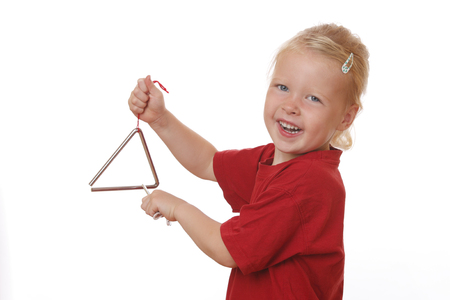 Portrait of a young girl playing a triangle on white backgroundの写真素材