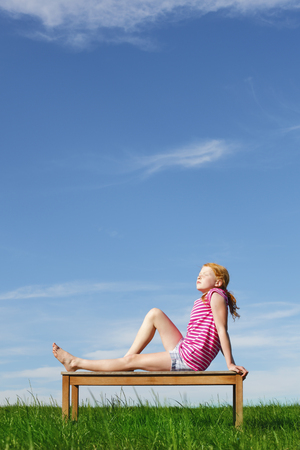 Happy young girl posing outdoors on an benchの写真素材