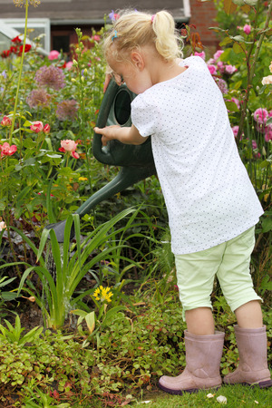 Young girl waters some flowers in the gardenの写真素材