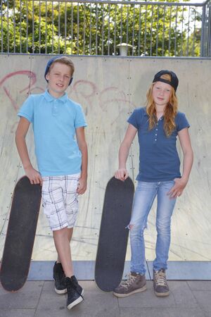 Cool young boy and girl outdoor with skateboardの写真素材