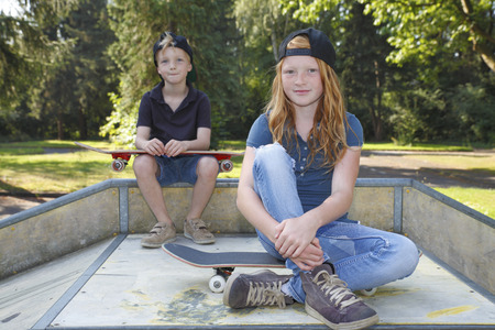 Cool young boy and girl outdoor with skateboardの写真素材
