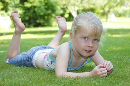 Happy young girl lying outdoors in a meadowの写真素材