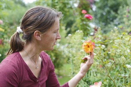 Young woman enjoys some flowers in the gardenの写真素材
