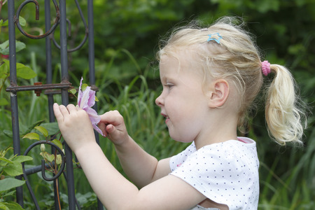 Adorable young girl enjoys some flowers in the gardenの写真素材