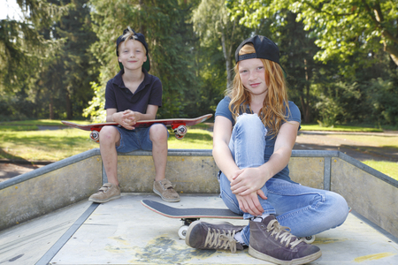 Cool young boy and girl outdoor with skateboardの写真素材
