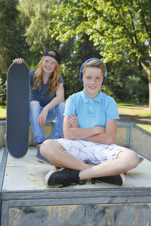Cool young boy and girl outdoor with skateboardの写真素材