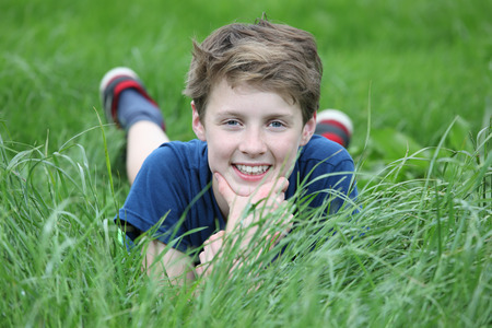 Happy young teenage boy lying in a meadowの写真素材