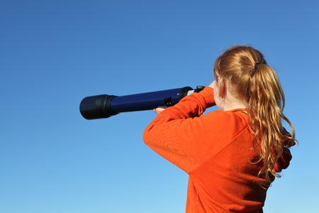 Young girl with telescope watching the skyの写真素材