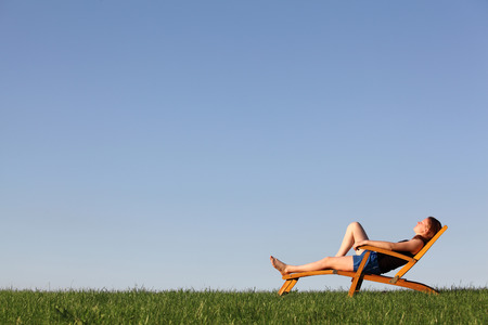 Beautiful young girl relaxes on a deckchair in a meadowの写真素材