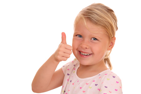 Portrait of a smiling young girl with thumbs up on white backgroundの写真素材