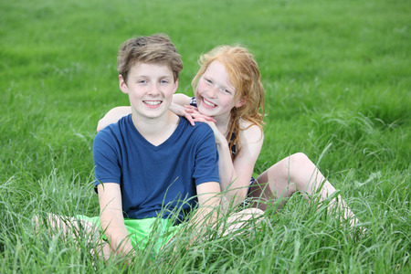 Two happy young teenager sitting in a meadowの写真素材
