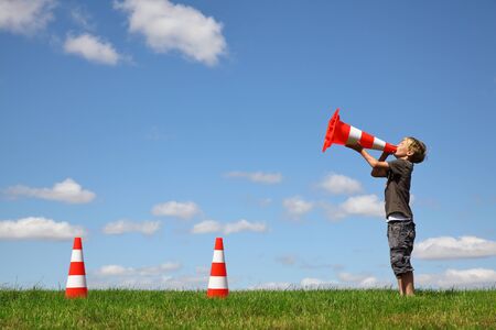 Young boy with traffic cones on a green meadowの写真素材