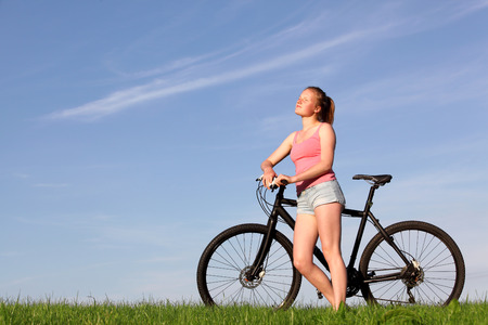 Beautiful young girl enjoys a ride on a bike outsideの写真素材
