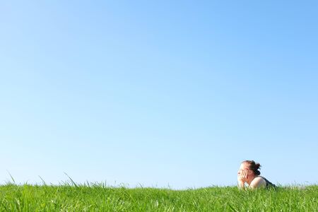 Relaxed young girl enjoys lying in grassの写真素材
