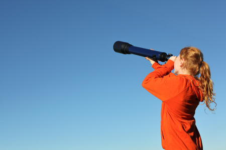 Young girl with telescope watching the skyの写真素材