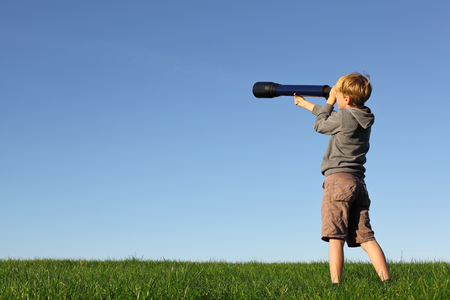 Young boy with telescope watching the skyの写真素材