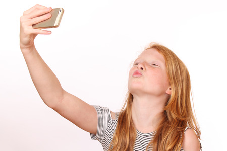 Portrait of a young girl taking a selfie on white backgroundの写真素材