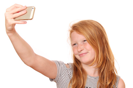 Portrait of a young girl taking a selfie on white backgroundの写真素材