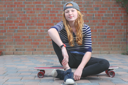 Portrait of a cool young teenage girl outdoors with skateboardの写真素材