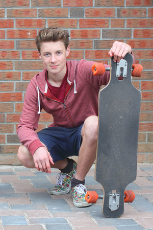 Portrait of a cool young teenage boy outdoors with skateboardの写真素材