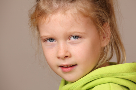 Portrait of a serious looking child girl on gray backgroundの写真素材