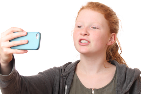 Portrait of a young girl taking a selfie on white backgroundの写真素材