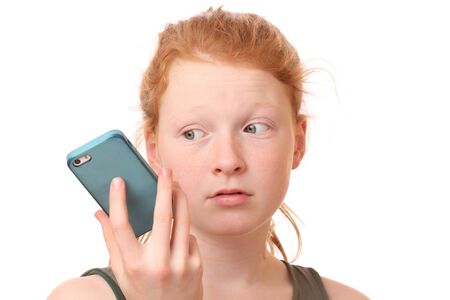 Portrait of a sad teenage girl holding mobile phone on white backgroundの写真素材