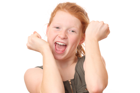 Portrait of a winning young girl flexing muscles on white backgroundの写真素材