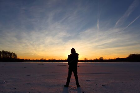 Young boy at lake at sunsetの写真素材