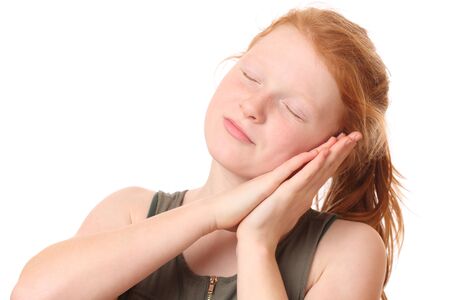 Portrait of a teenage girl doing sleep gesture on white backgroundの写真素材