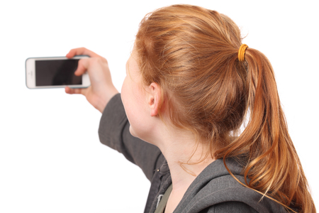Portrait of a young girl taking a selfie on white backgroundの写真素材