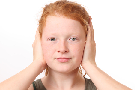 Portrait of a teenage girl covering ears with hands on white backgroundの写真素材