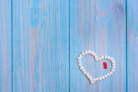 Red candy heart laying on white painted rustic wooden background.の写真素材