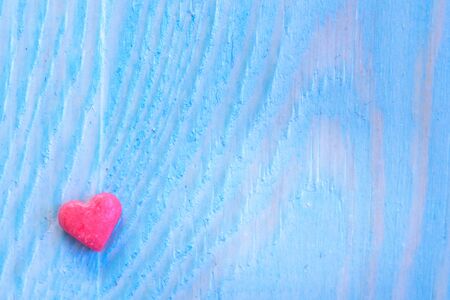 Red candy heart laying on light blue painted rustic wooden background.の写真素材