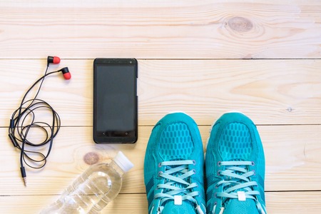 Flat lay shot of Sport equipment, shoes, water, earphone on wooden background.の写真素材