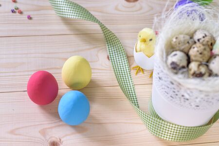 Easter with blue and white eggs in nest and gift box over white wood. Top view with copy space