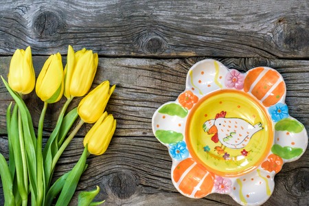 Fresh yellow tulip flowers on wooden table with ancient plates. Top view with copy space.  over wooden background.の写真素材