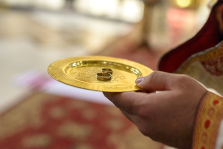 Priest holds plate with golden wedding rings.の写真素材