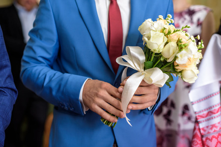 Groom holding wedding bouquet. Selective focus on bouquetの写真素材