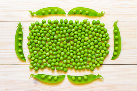 Green peas in white bowl on wooden background, top view or flat layの写真素材