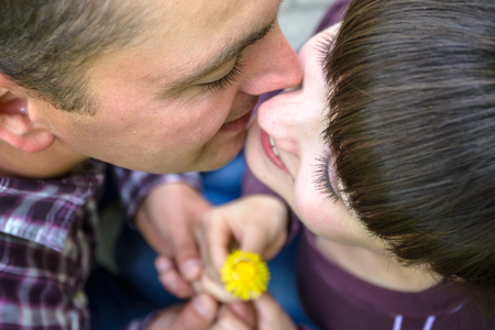 attractive couple with golden ring on dandelion arms holding together looking to each other kissingの写真素材