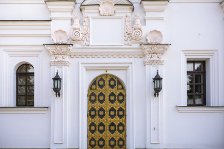 Old wrought iron metal gate with gold in the white brick wall of the buildingの写真素材