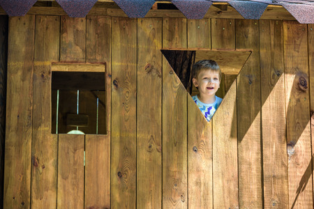 cute young boy looking through the window at the playground.の写真素材