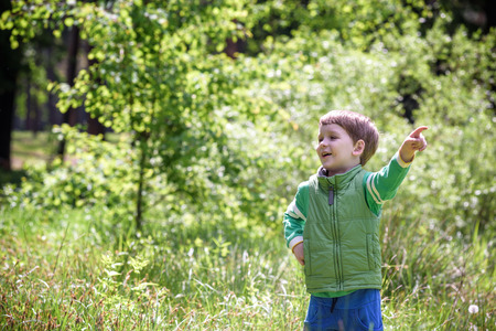 Five year old boy looking and pointing his finger at the strange treeの写真素材