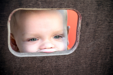 Curious kid spying through the hole in the wooden wall on playground.の写真素材