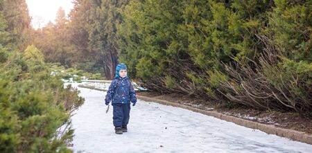 Winter portrait of kid boy in colorful clothes, outdoors. Active outoors leisure with children in winter on cold snowy days. Happy toddler child having fun with snow in forestの写真素材