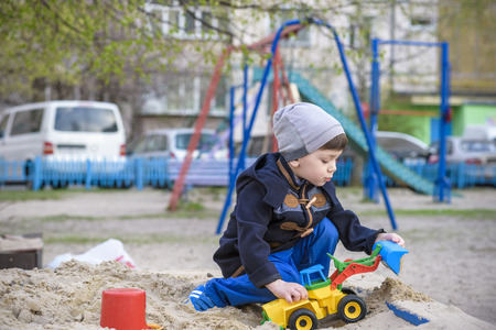 Little boy playing with children excavator in the sandbox.の写真素材