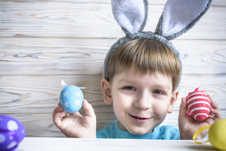 Kid with bunny ears peeking from beneath the table - waiting for the easter rabbit playing with...
