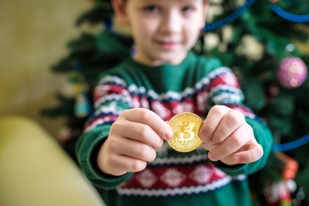 One Bitcoin in the hand of young boy. Concept. Crypto digital gold.の写真素材